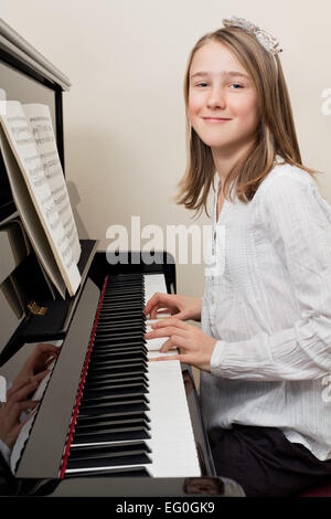 Photo of a young girl playing the piano at home. Stock Photo