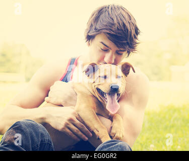Young man holding puppy outdoors
