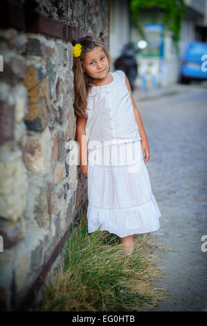 Girl (6-7) leaning against wall Stock Photo