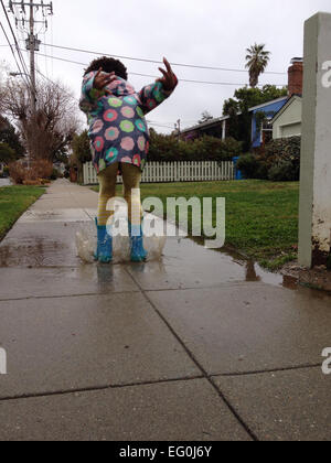 Girl jumping into puddle Stock Photo