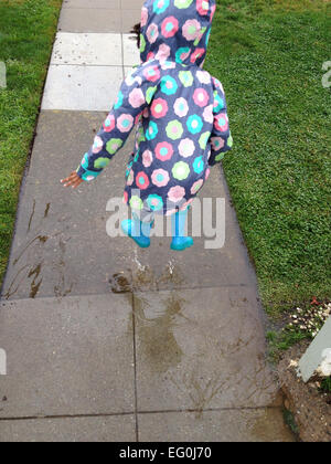 Girl jumping into puddle Stock Photo