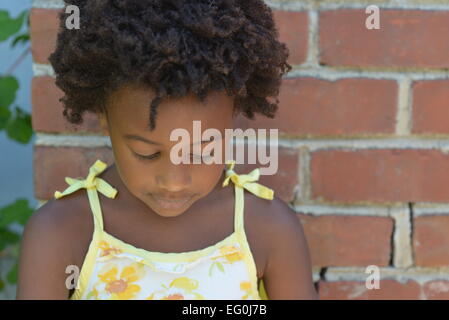 Girls standing by a brick wall looking down Stock Photo