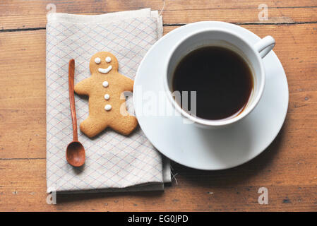 Cup of coffee and gingerbread man with spoon on wooden table Stock Photo