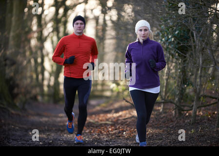 Couple On Winter Run Through Woodland Stock Photo