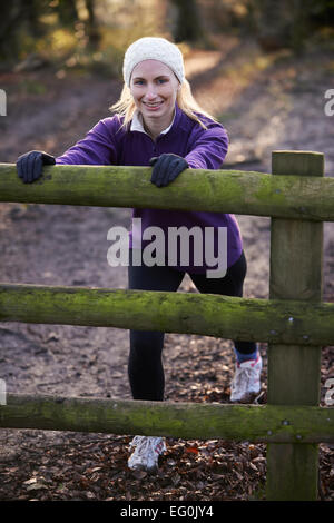 Woman Stretching On Run Through Winter Woodland Stock Photo