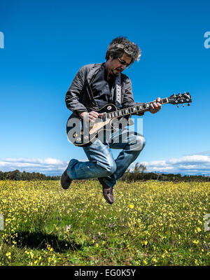Man playing guitar in a field Stock Photo