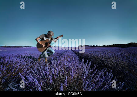 Man playing guitar in lavender field Stock Photo
