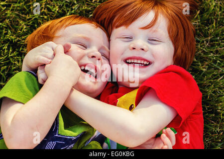 Two happy boys lying on grass laughing