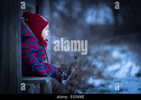 Young boy sitting on bench outside Stock Photo