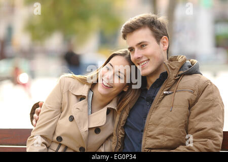 Couple in love sitting in a bench hugging in an urban park in winter Stock Photo