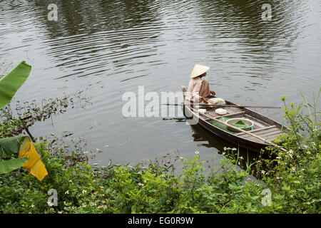 Traditionally dressed old woman fishing from her small fishing boat, Hoi An, Vietnam, Indochina, Southeast Asia, Asia Stock Photo