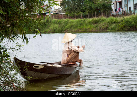 Traditionally dressed old woman fishing from her small fishing boat, Hoi An, Vietnam, Indochina, Southeast Asia, Asia Stock Photo