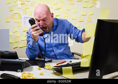 Angry boss / man screaming on the phone at his office. Stock Photo