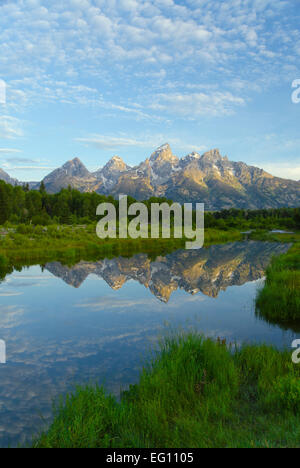 Fantastic sunrise in Grand Teton, mountains reflected on a quiet pond branching from the Snake river. Mirror still reflection, painted sky, forest. Stock Photo