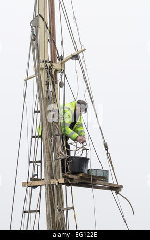 A man working on the mast of a sailing boat. Stock Photo
