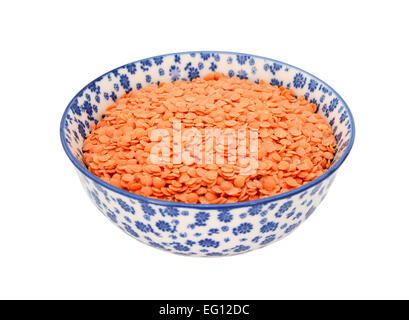 Red lentils in a blue and white porcelain bowl with a floral design, isolated on a white background Stock Photo