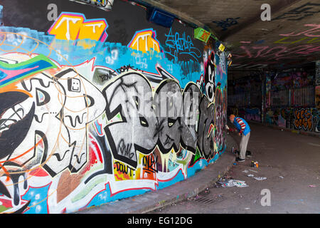 Street artist at work at 'The Tunnel', an authorised graffiti area at Leake Street near Waterloo Station in London Stock Photo