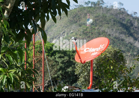 Satellite dish on rooftop and communications tower on hillside Stock Photo