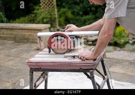 man using water cooled ceramic tile cutting machine release available Stock Photo