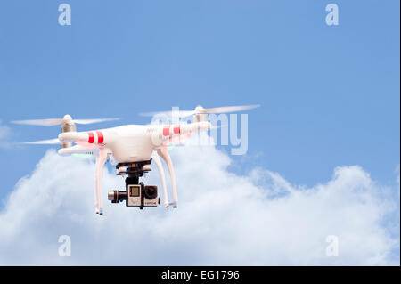 Quadcopter or drone flying against a blue sky with clouds Stock Photo