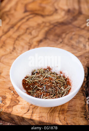 Mixed dried herbs with paprika in small bowl over olive wood background, selective focus Stock Photo