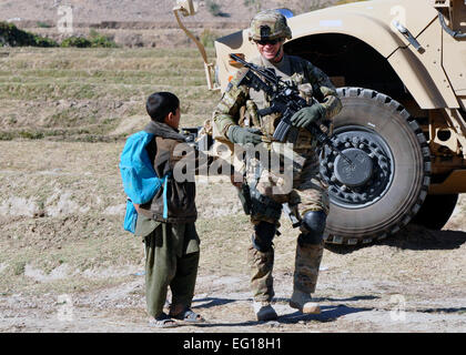 U.S. Army Capt. Garrett Gingrich, originally from Waterloo, Iowa, the commander of Charlie Company, 1st Battalion, 133rd Infantry Regiment, talks to an Afghan child at a mounted patrol base in the Alingar district on Nov. 10, 2010. The Commandos were investigating an incident in the district where anti-government criminals burned supplies, including more than 800 copies of the Quran, at a girls' school in the district.  Chief Master Sgt. Richard Simonsen Stock Photo