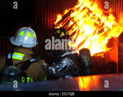 Left U.S. Air Force Col. Trent Edwards, the 28th Mission Support Group commander, trains as a firefighter during a controlled indoor fire with Bill Cina, a 28th Civil Engineer Squadron fire truck operator, at Ellsworth Air Force Base, S.D., Jan. 27, 2011.  The fire is set inside a training building used solely by the fire department.  Senior Airman Anthony Sanchelli Stock Photo