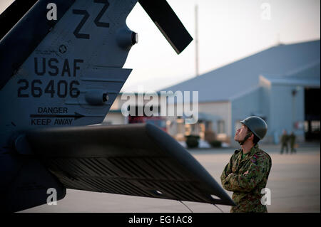 A member of the Japan Ground Self-Defense Force observes a U.S. Air Force HH-60 Pave Hawk helicopter at Yokota Air Base, Japan, March 13, 2011. JGSDF members and a joint team of U.S. Air Force and Marine personnel discussed the possibility of using Yamagata as a fuel staging area to refuel aircraft assisting with Japan's earthquake and tsunami recovery efforts.  Staff Sgt. Samuel Morse Stock Photo