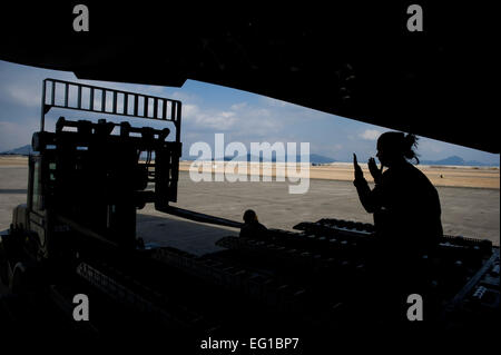 MARINES CORPS AIR STATION IWAKUNI, Japan – Senior Airman Kristina Cyphert, 535th Airlift Squadron, directs a forklift on board a C-17 Globemaster III to download its cargo here March 25. The C-17 flew into Marines Corps Air Station Iwakuni to pick up marines from Marine Wing Support Squadron MWSS 171 to drop off them at Sendai Airport. MWSS-171 where heading to Sendai Airport to setup portable showers to bring humanitarian assistance to Japan in part of Operation Tomodachi. Staff Sgt. Jonathan Steffen Stock Photo