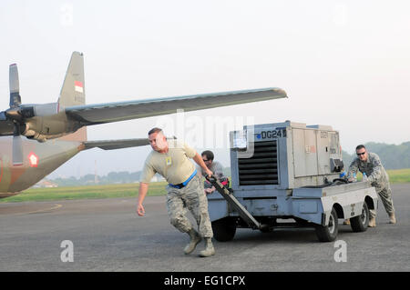 U.S. Air Force Master Sgt. Greg Lilly, a production supervisor with the 374th Aircraft Maintenance Squadron at Yokota Air Base, Japan, leads fellow maintainers in moving a generator cart in preparation for the first flight mission of Exercise Cope West 11 at Halim Air Base, Indonesia, June 20, 2011. Three C-130s and more than 70 Airmen from Yokota, as well as one Indonesian Air Force C-130, participated in this weeklong bilateral field training exercise designed to enhance the readiness and combined interoperability between the U.S. and Indonesian air forces.  Capt. Raymond Geoffroy Stock Photo