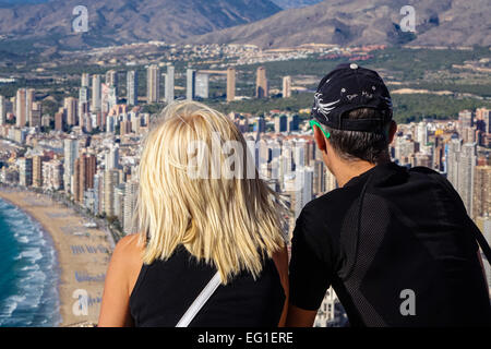 Tourists wearing sports clothing admiring the view of Benidorm, Costa Blanca, Spain. Taken from close behind them. Stock Photo