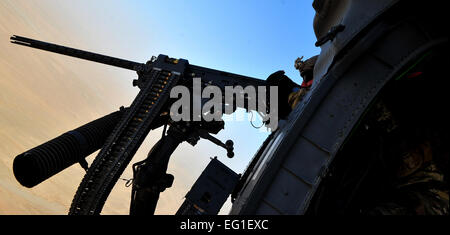 An aircrew member from the 26th Expeditionary Rescue Squadron ERQS mans the .50-caliber machine gun mounted to a HH-60G Pave Hawk helicopter over Afghanistan, Feb. 5, 2012. The 26th ERQS compliments their traditional personnel recovery mission with medical evacuation operations in Afghanistan’s Regional Command Southwest.  Senior Airman Tyler Placie Stock Photo