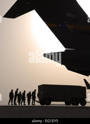 U.S. Air Force Airmen from the 8th Expeditionary Air Mobility Squadron EAMS ramp section steer a generator as it is pulled into a U.S. Air Force C-17 Globemaster III cargo aircraft at an undisclosed location in Southwest Asia, Feb. 11, 2012. Airmen from the 8th EAMS ramp section load aircraft with cargo after the cargo processing section has prepped the cargo for transportation.  Staff Sgt. Nathanael Callon Stock Photo