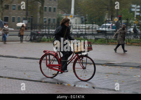 woman biking on a rainy day in Amsterdam Stock Photo