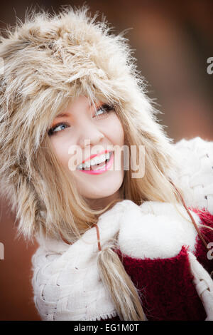 Winter fashion. Closeup smiling young woman wearing fashionable wintertime clothes fur cap outdoor portrait Stock Photo