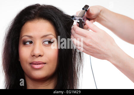 Hairstyling. attractive mixed race woman with long hair making hairstyle hairdo with electric hair curler iron on white Stock Photo