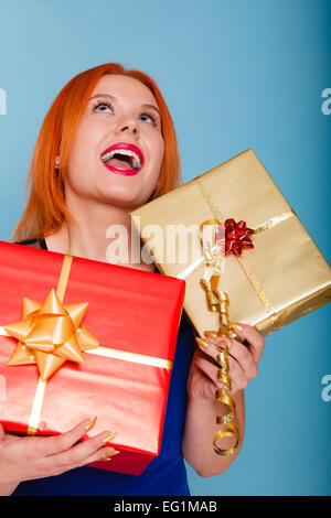 People celebrating holidays, love and happiness concept - happy joyful red hair girl with gift boxes studio shot on blue backgro Stock Photo