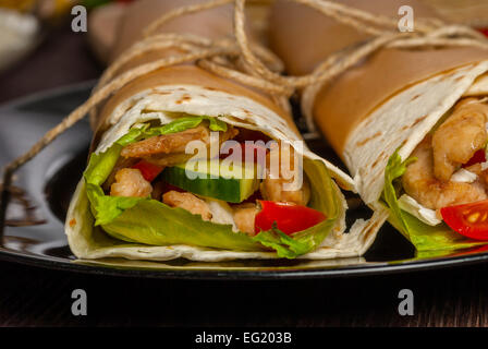 Mexican tortilla wrap with meat and vegetables on wood table Stock Photo