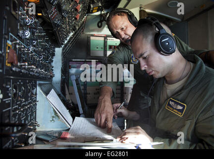 Senior Master Sgt. Timothy Nichols, left, discusses fuel consumption with Tech. Sgt. Francisco Guerrero-Vasquez on the flight deck of a C-5B Galaxy on a Pacific channel mission. Both Air Force Reserve aviators are assigned to the 312th Airlift Squadron, Travis Air Force Base, Calif. Nichols is a flight engineer evaluator and Guerrero-Vasquez is a flight engineer.  Lt. Col. Robert Couse-Baker Stock Photo