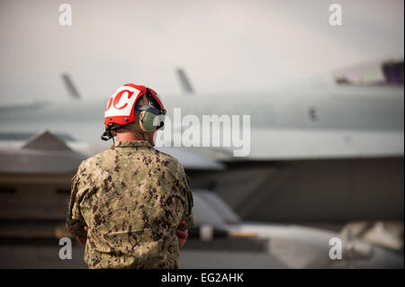 An aircraft maintainer from the 135th Electronic Attack Squadron, Naval Air Station Whidbey Island, Wash., watches as his assigned aircraft passes by for a training mission after pre-flight checks Jan. 29, 2014, at Nellis Air Force Base, Nev. Joint service aircrews play their part in “Blue Force” operations, supporting the simulated air-war against “Red Forces” organized by the 57th Adversary Tactics Group.  Airman 1st Class Joshua Kleinholz Stock Photo