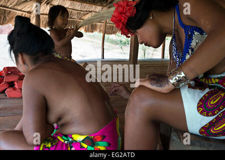 Women native embera doing a tattoo in the Village of the Indian Embera Tribe, Embera Village, Panama. Panama Embera people India Stock Photo