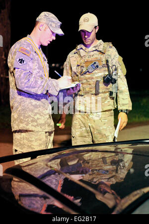 U.S. Army Sgt. Mark Newcomb, Alpha Company 179, and U.S. Air Force Tech. Sgt. Larry Mansell exchange information at a checkpoint during the night in Moore, Okla., May 22, 2013. Checkpoints have been set up all over the city to ensure residents safety and security after the devastating tornado that struck May 20, 2013.  by Staff Sgt. Caroline Hayworth Stock Photo
