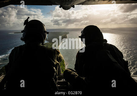 U.S. Air Force Senior Airman Timothy Oberman, left, and Staff Sgt. Nick Alarcon watch out the back of a U.S. Air Force C-130H Hercules cargo aircraft after dropping the first pallet of humanitarian goods to the island of Ulal Dec. 11, 2012. Operation Christmas Drop is a non-profit organization powered by volunteers from Andersen Air Force Base and the local Guam community. Oberman and Alarcon are loadmasters with the 36th Airlift Squadron, Yokota Air Base, Japan.  Tech. Sgt. Samuel Morse Stock Photo