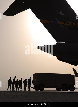 Airmen from the 8th Expeditionary Air Mobility Squadron ramp section steer a generator as it is pulled into a C-17 Globemaster III in Southwest Asia, on Feb. 11, 2012. The Airmen are air transportation specialists from the 8th EAMS ramp section, which loads aircraft with cargo after the cargo processing section has prepped the cargo for transportation. Staff Sgt. Nathanael Callon Stock Photo