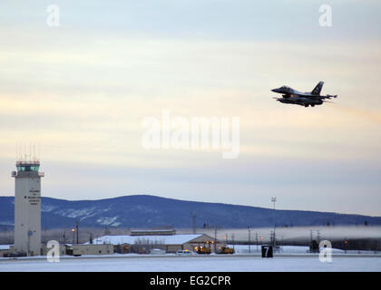 One of 14 F-16 Fighting Falcons from the 18th Agressor Squadron takes off from Eielson Air Force Base, Alaska, shortly after sunrise Jan. 17, 2015, in transit to Hickam Air Force Base, Hawaii, and Andersen Air Force Base, Guam to participate in the CENTURY ALOHA and COPE NORTH exercises. More than 150 maintainers will keep the Agressors in the air during the exercises, which are meant to prepare U.S. Airmen, Sailors and Marines along with coalition partners in the Pacific theater of operations for contingency operations if the need arises.  Master Sgt. Karen J. Tomasik Stock Photo