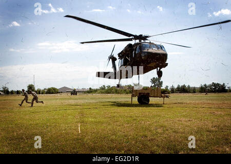 Reservists assigned to the 434th Force Support Squadron make their way from under an Army Reserve UH-60 Black Hawk after hooking a small trailer to the hovering helicopter for transport during a joint training exercise July 23, 2013, at Grissom Air Reserve Base, Ind.  Tech. Sgt. Douglas Hays Stock Photo