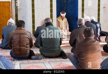 An imam is sitting and praying in a mihrab during the friday afternoon prayer in a mosque Stock Photo