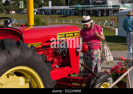 Lady views red David Brown 990 Implematic series classic tractor in immaculate condition & on display at Great Yorkshire Show, Harrogate, England, UK. Stock Photo