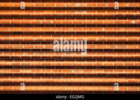 Part of the wall of the house of tan brick red with a shadow from the grid. Stock Photo