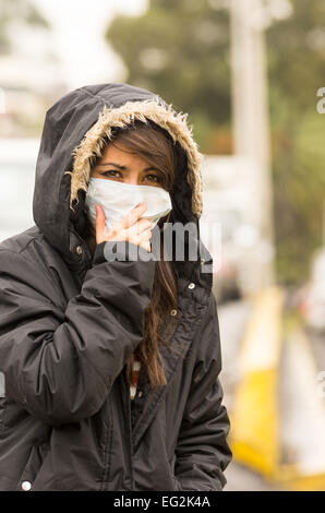 young girl walking wearing jacket and a mask in the city street concept of  pollution Stock Photo